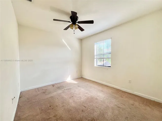 an empty room with a ceiling fan and carpet