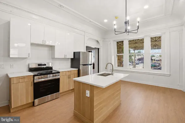 a kitchen with stainless steel appliances granite countertop a sink a stove a refrigerator cabinets and a dining table
