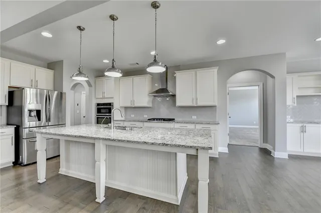 a large kitchen with stainless steel appliances kitchen island granite countertop a stove and a sink