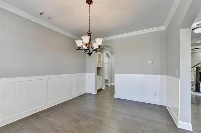a view of a room with wooden floor chandelier and windows