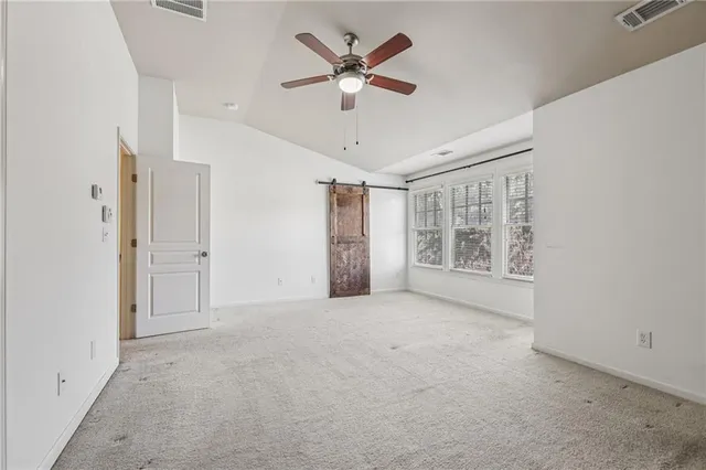 an empty room with chandelier fan and windows