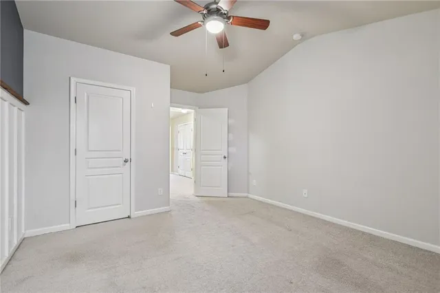 an empty room with chandelier fan and windows