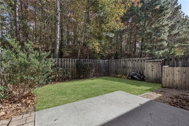 a view of a backyard with large trees and wooden fence