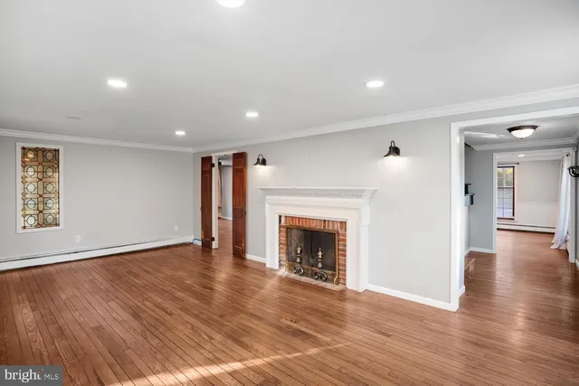a view of an empty room with wooden floor fireplace and a window