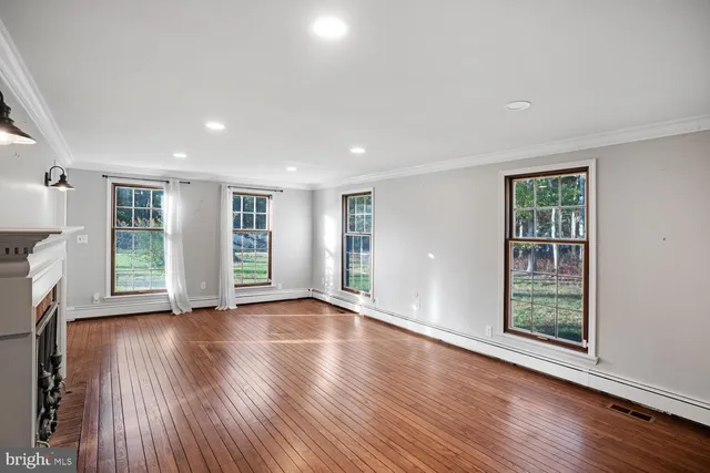 a view of an empty room with window and wooden floor