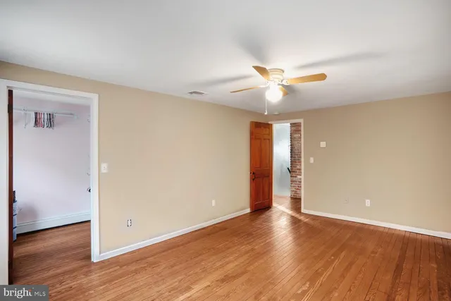 an empty room with wooden floor front door and windows