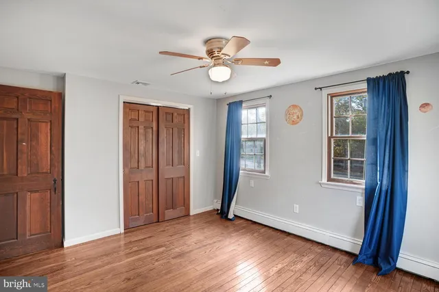 an empty room with wooden floor chandelier fan and closet area