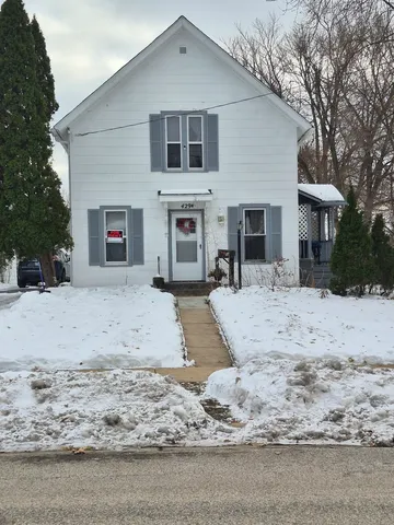 a view of a white house with a yard covered with snow in the road