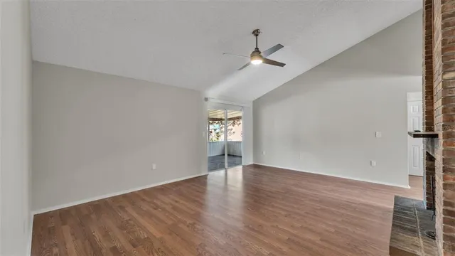 an empty room with wooden floor chandelier fan and windows