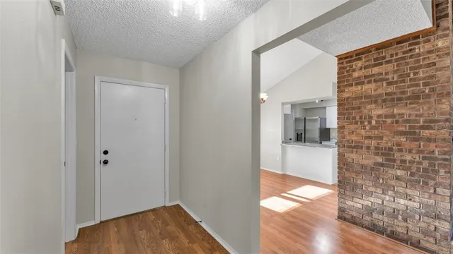 a view of a hallway with wooden floor and a bathroom