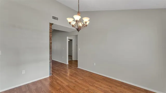a view of a hallway with a chandelier fan and wooden floor