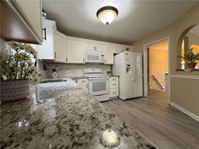a kitchen with stainless steel appliances granite countertop white cabinets and a sink