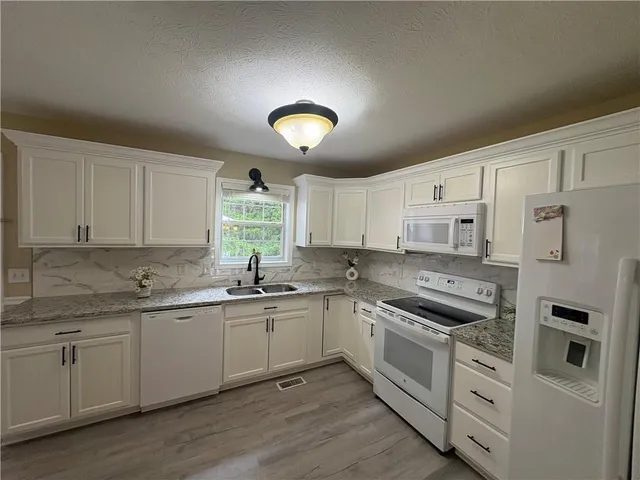 a kitchen with cabinets appliances a sink and a window