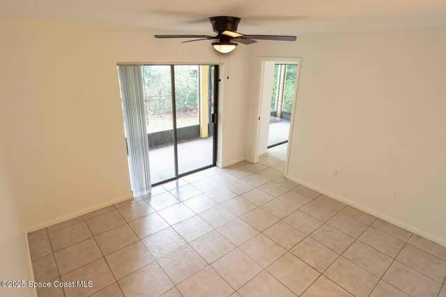an empty room with windows and chandelier fan
