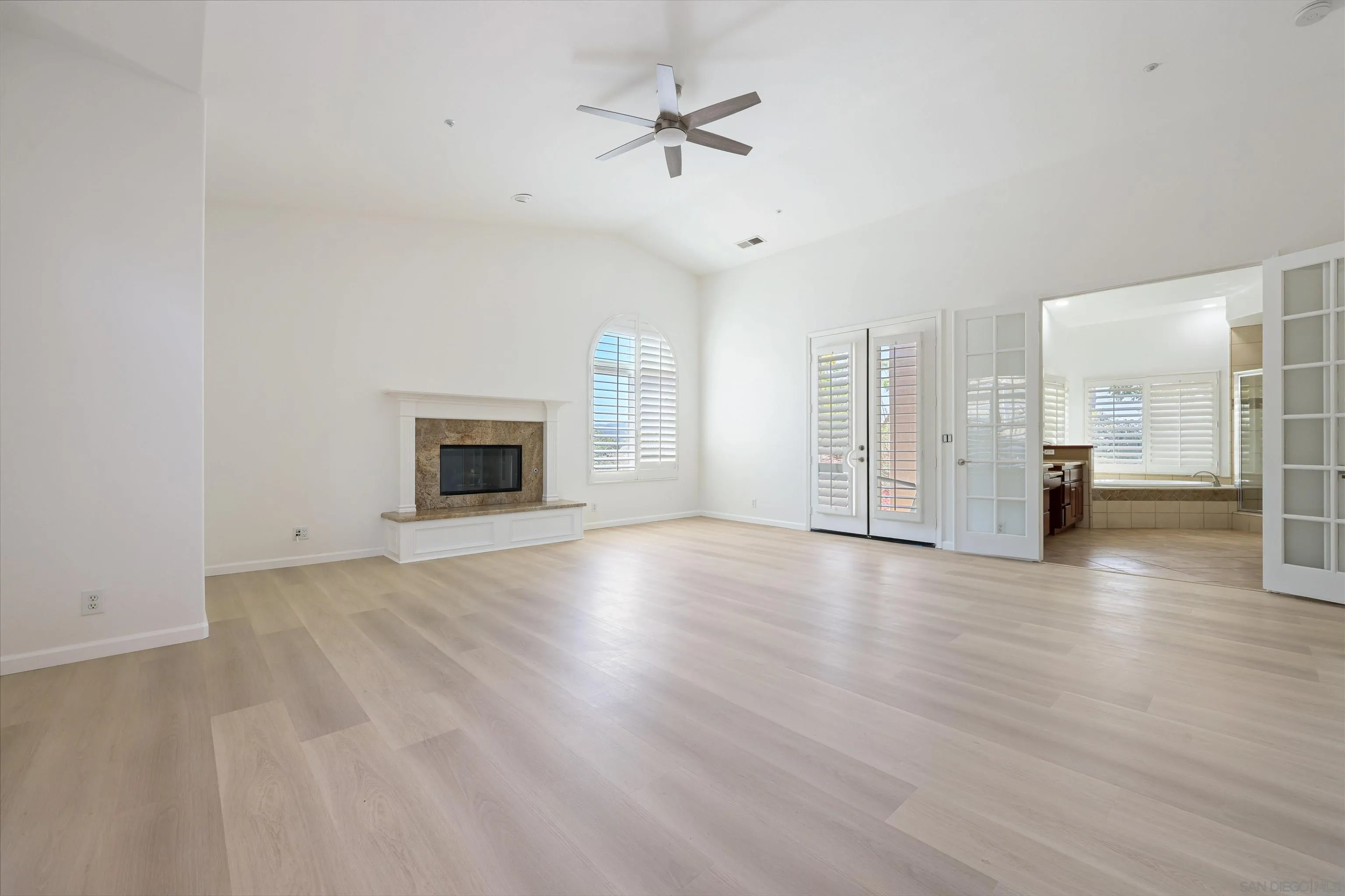 26335 Engelmann Road Valley Center, CA 92082 - Photo 19 of 42 an empty room with wooden floor fireplace and a ceiling fan