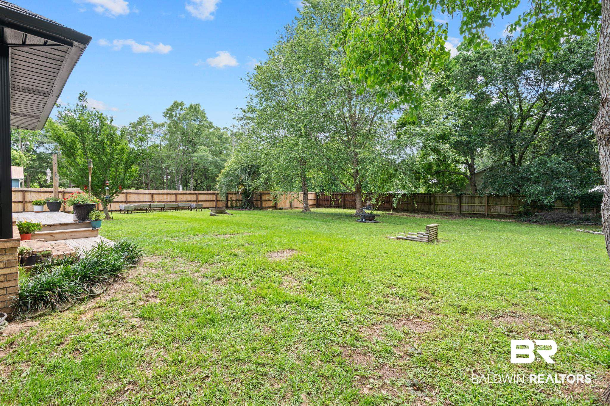 5936 Lundy Road Theodore, AL 36582 - Photo 32 of 32 Expansive backyard featuring a large grassy area, mature trees, a wood privacy fence, and a spacious wood deck
