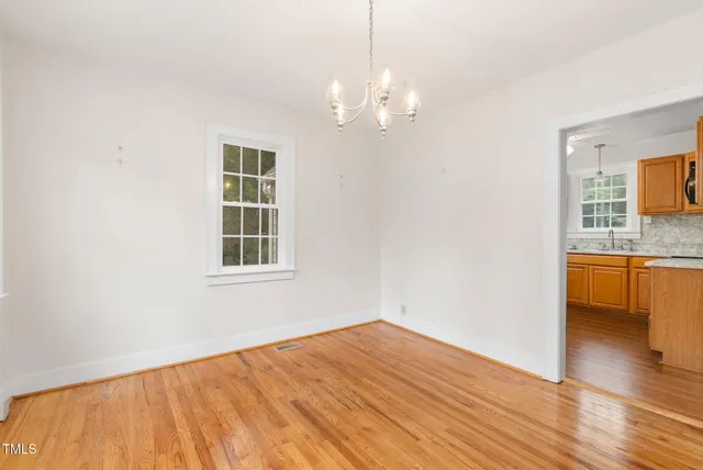a view of an empty room with chandelier fan and a window