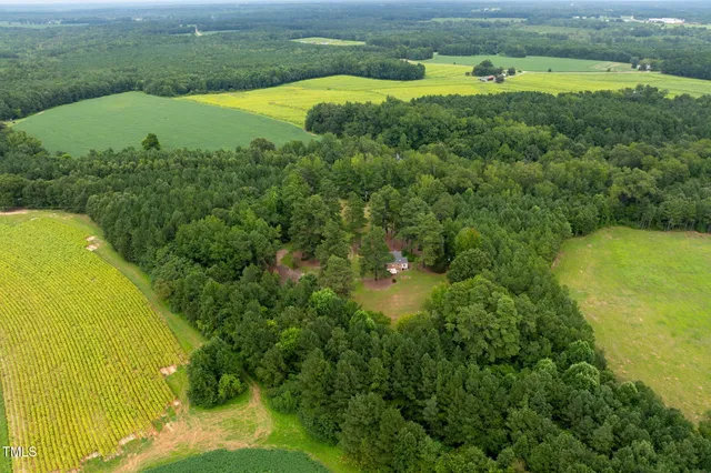 an aerial view of residential house with outdoor space and trees all around