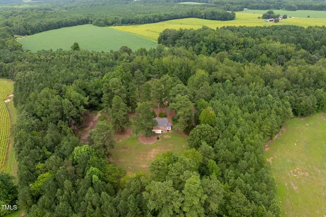 an aerial view of residential house with outdoor space and trees all around