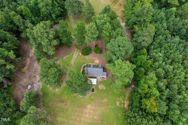 an aerial view of residential house with outdoor space and trees all around