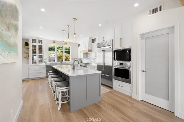 a kitchen with stainless steel appliances a stove a sink and a refrigerator with wooden floor