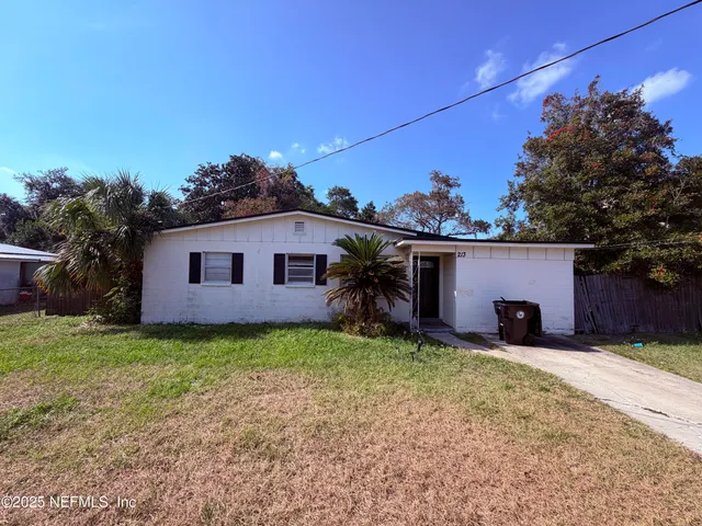 a view of a house with a yard and a large tree