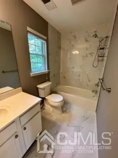 a bathroom with a granite countertop bathtub sink vanity mirror and toilet