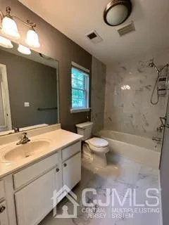 a bathroom with a granite countertop sink mirror vanity and toilet