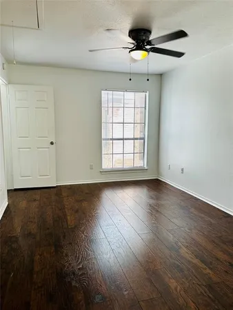 an empty room with wooden floor chandelier fan and windows