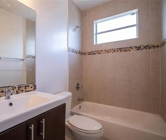 a bathroom with a bathtub shower sink mirror vanity and toilet