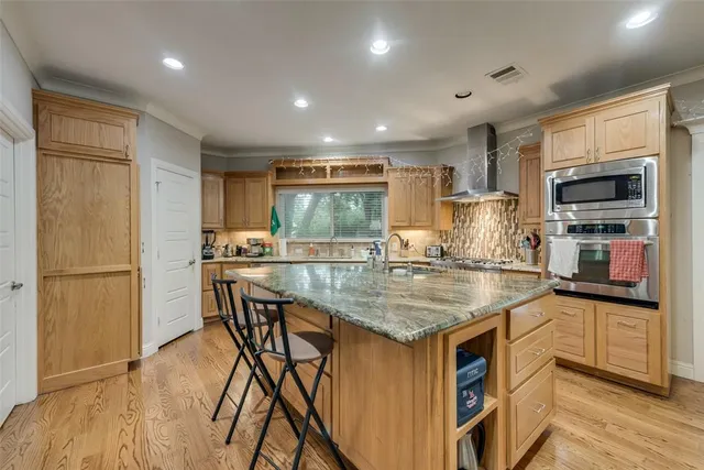 a kitchen with stainless steel appliances granite countertop a refrigerator a stove a sink a microwave and island