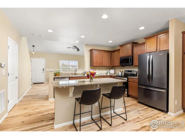 a kitchen with stainless steel appliances kitchen island granite countertop a refrigerator and a sink