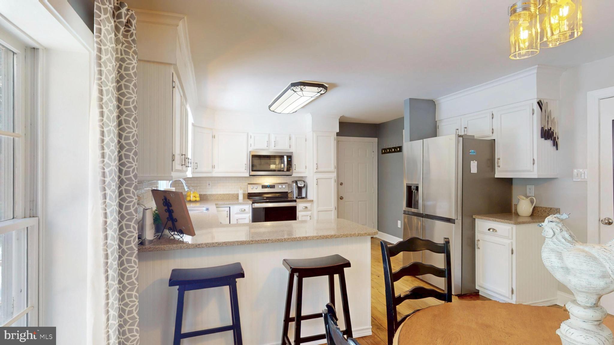 20192 Cockerill Road Purcellville, VA 20132 - Photo 16 of 59 a kitchen with stainless steel appliances a stove a refrigerator counter tops and white cabinets with wooden floor