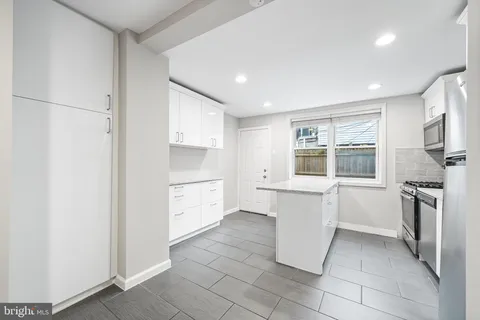 a kitchen with a refrigerator and white cabinets