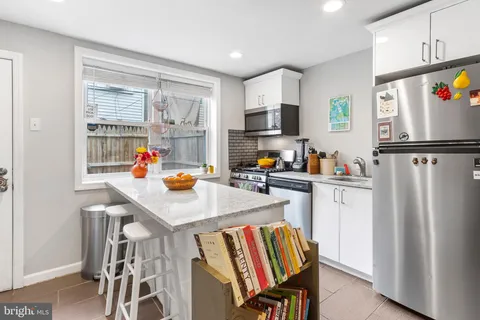 a kitchen with stainless steel appliances a refrigerator a sink a stove and a refrigerator with wooden floor