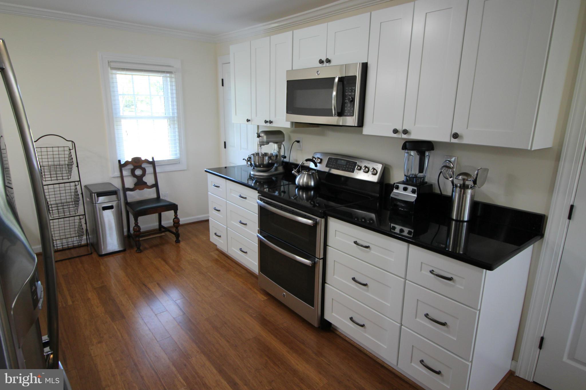 2280 Reliance Road Middletown, VA 22645 - Photo 9 of 28 a kitchen with granite countertop white cabinets and black appliances
