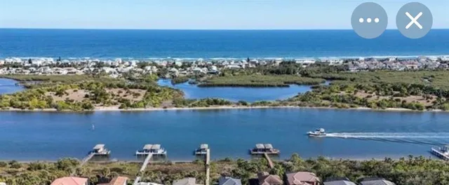 an aerial view of ocean and residential houses with outdoor space