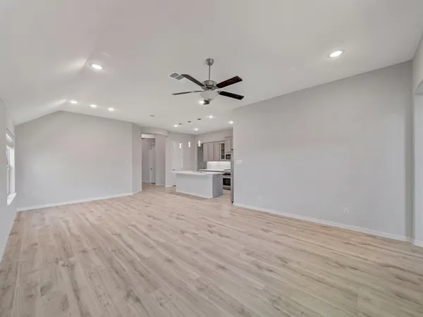 a view of an empty room with a ceiling fan and wooden floor