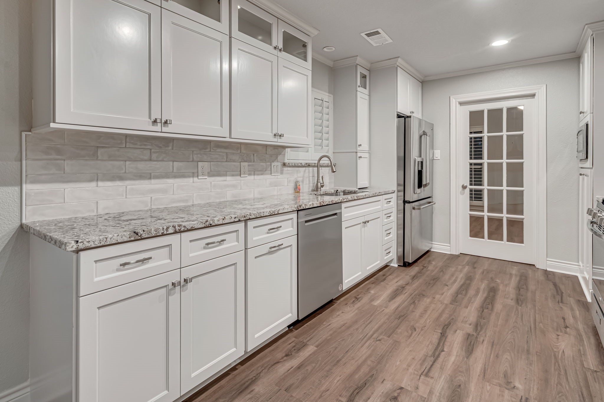 4702 Spring Lane Baytown, TX 77521 - Photo 13 of 34 a kitchen with stainless steel appliances granite countertop a sink dishwasher a refrigerator and white cabinets with wooden floor