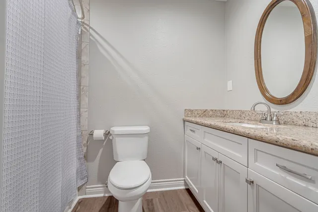 a bathroom with a granite countertop toilet sink and mirror