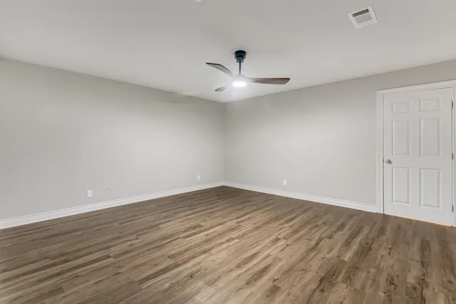 an empty room with wooden floor and ceiling fan