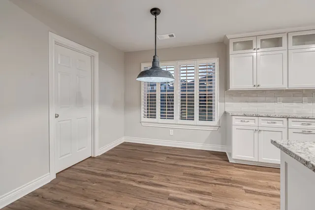 a view of an empty room with a window and kitchen view