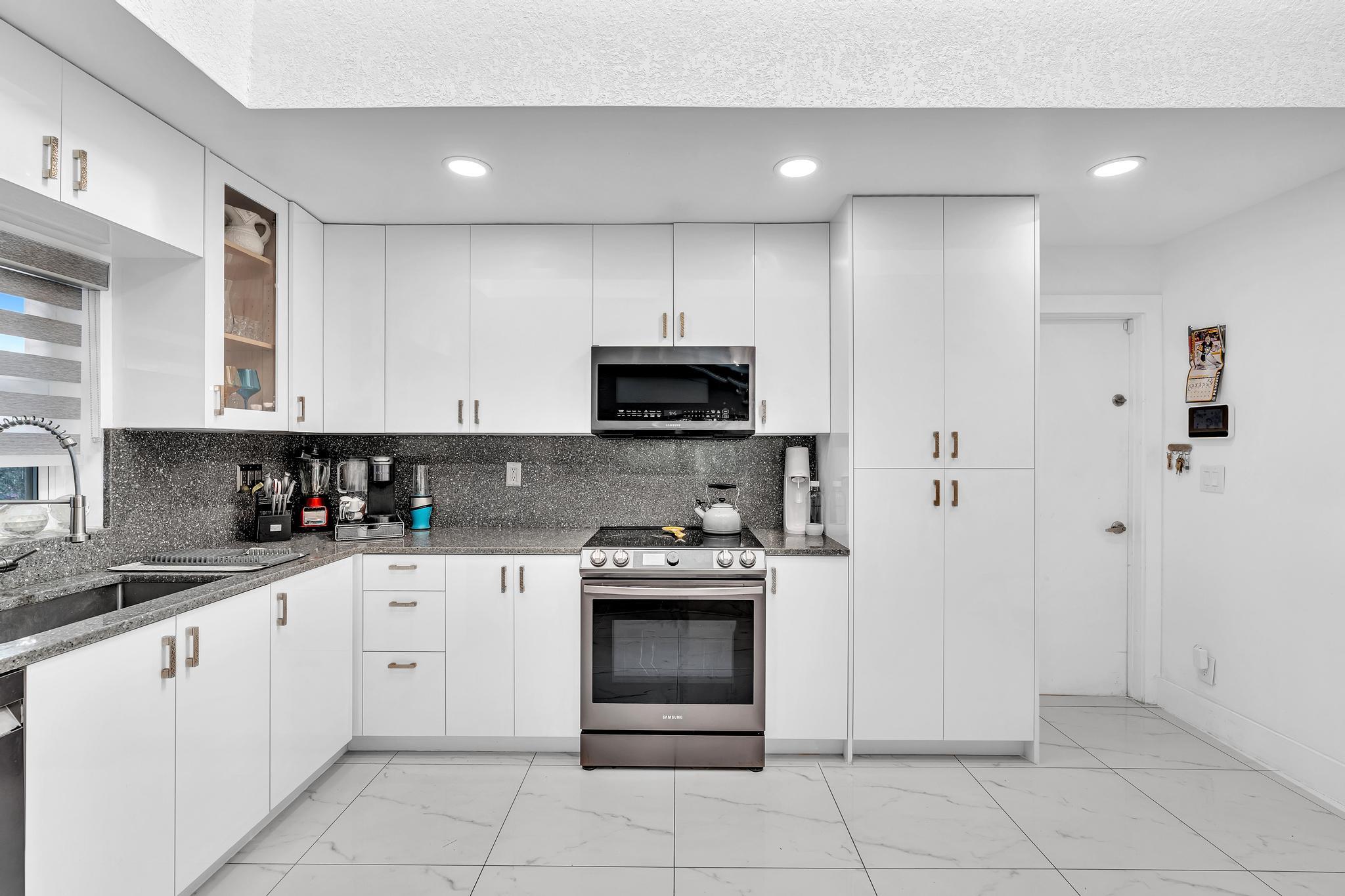 20104 Back 9 Drive Boca Raton, FL 33498 - Photo 18 of 78 a kitchen with granite countertop white cabinets and stainless steel appliances
