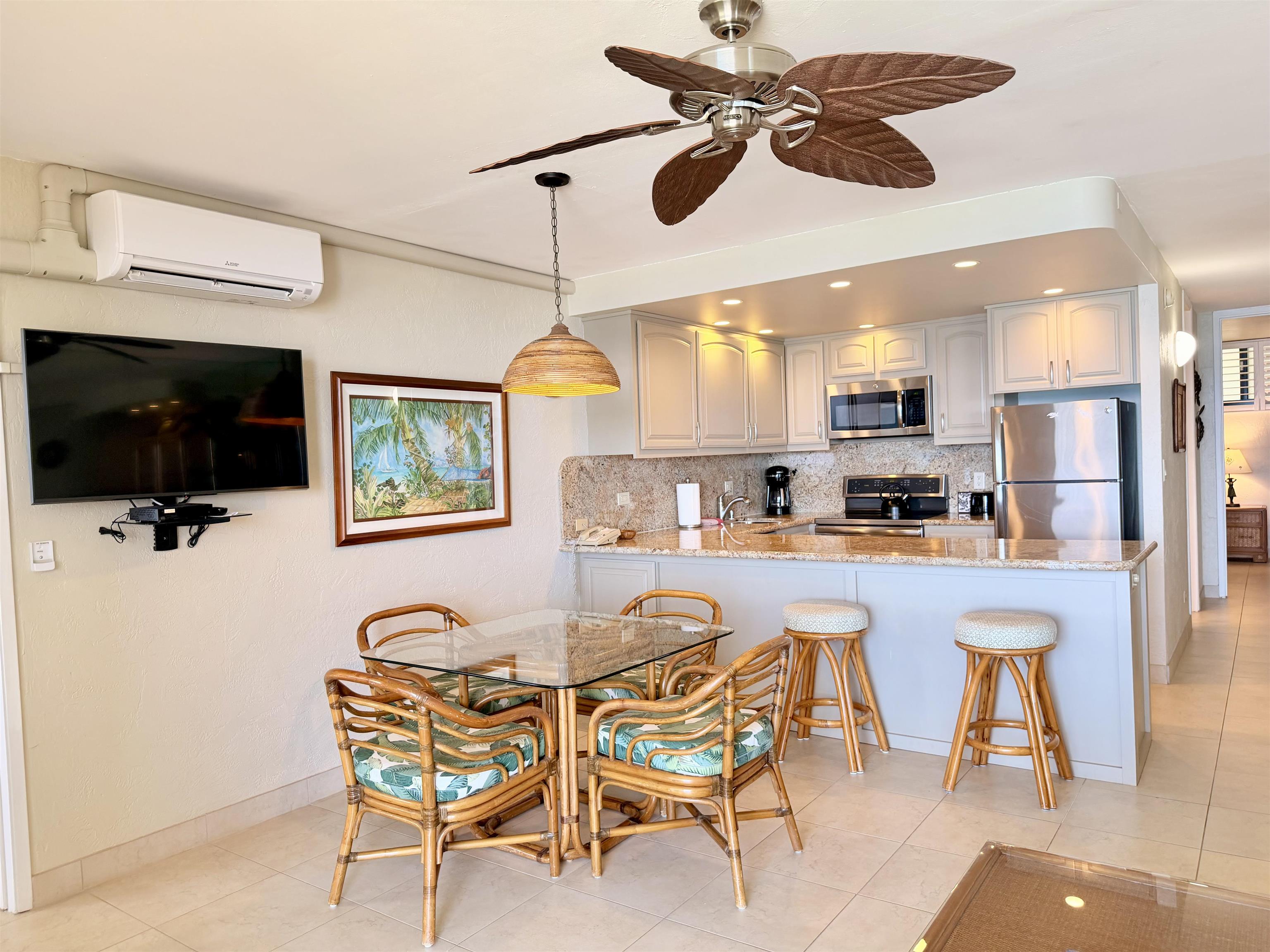 3543 Lower Honoapiilani Road, Unit L302 Lahaina, HI 96761 - Photo 14 of 45 a kitchen with stainless steel appliances kitchen island granite countertop a dining table chairs refrigerator and sink
