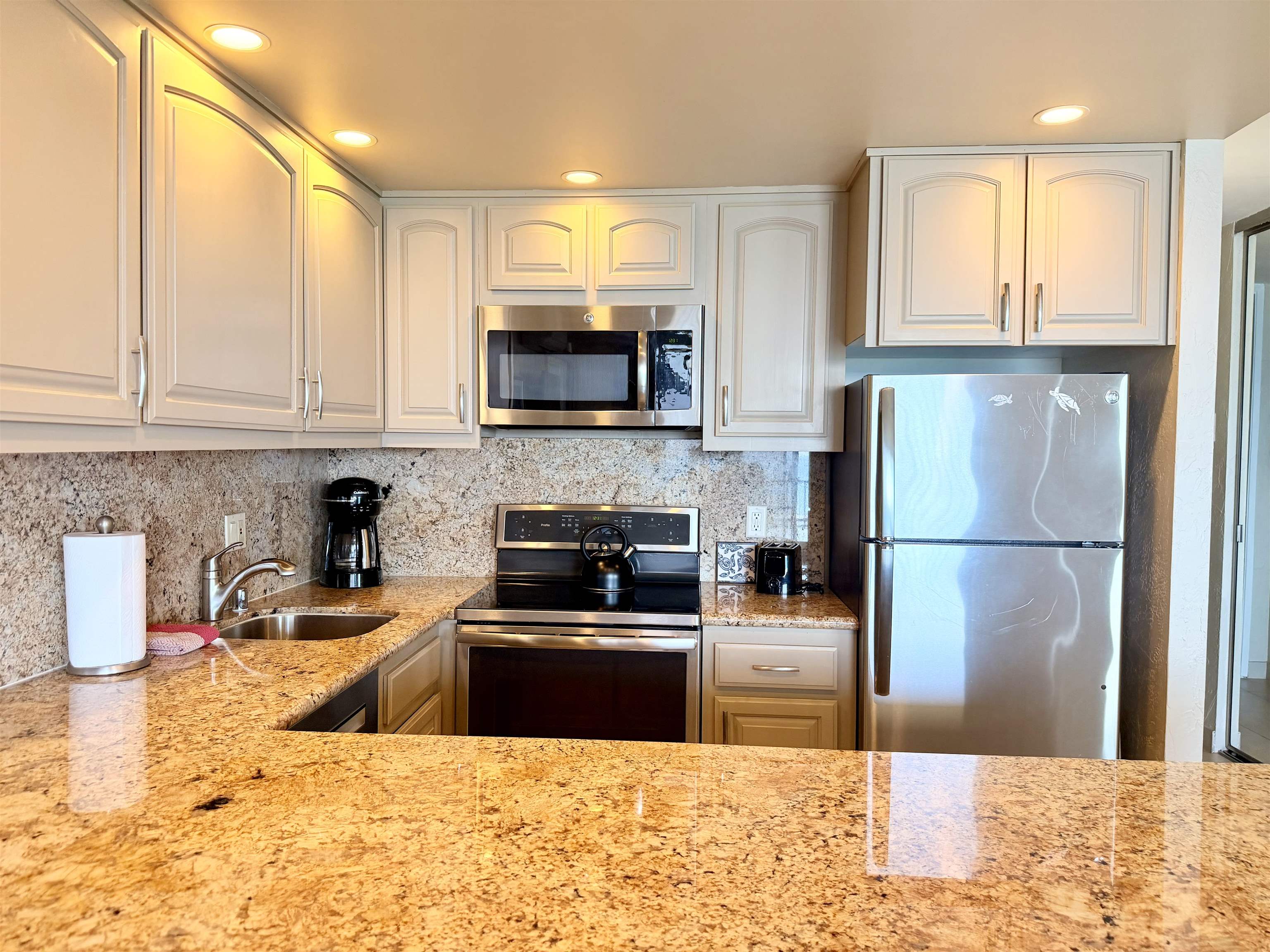 3543 Lower Honoapiilani Road, Unit L302 Lahaina, HI 96761 - Photo 5 of 45 a kitchen with stainless steel appliances a stove a sink a microwave a refrigerator and cabinets