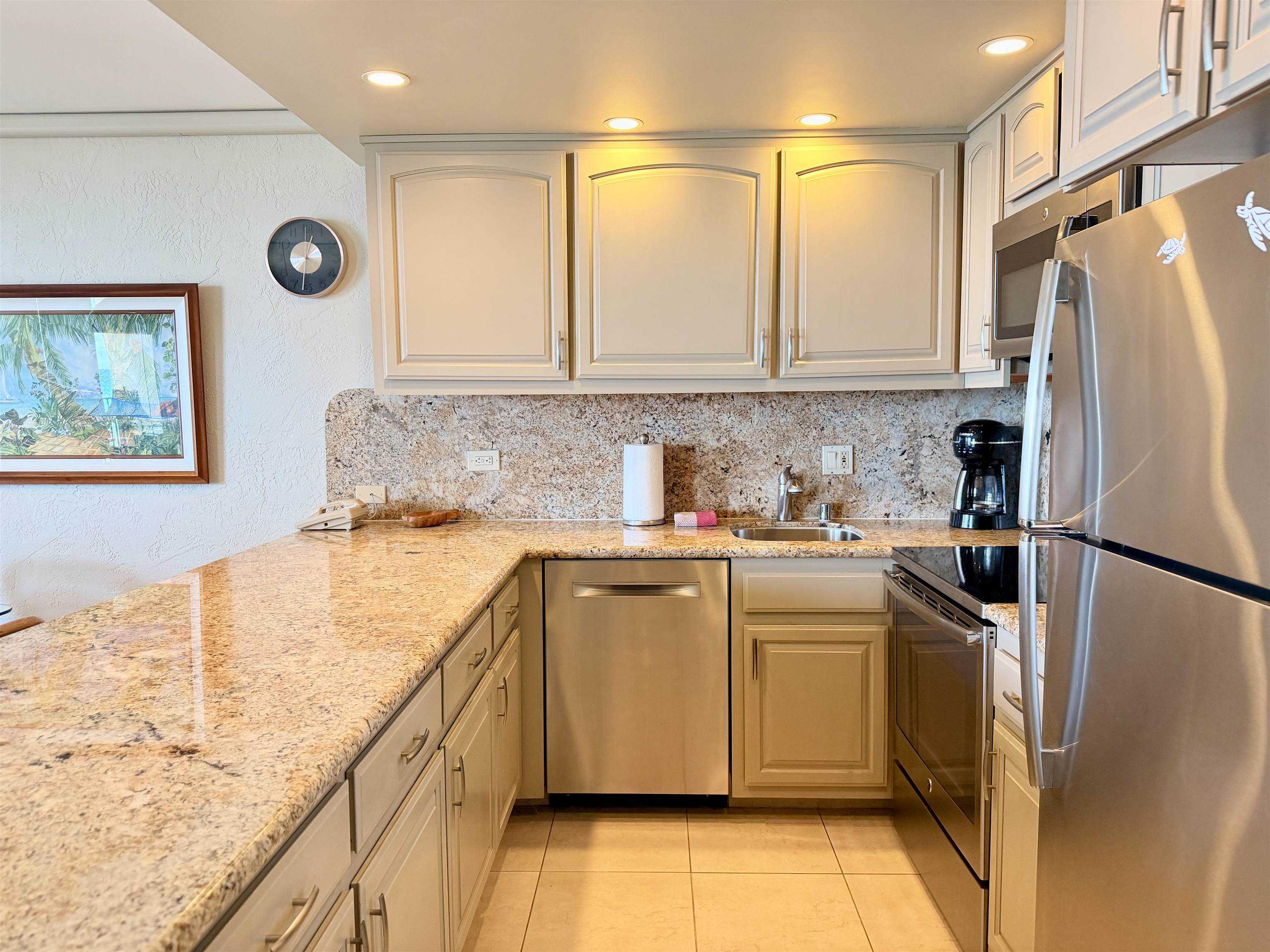 3543 Lower Honoapiilani Road, Unit L302 Lahaina, HI 96761 - Photo 6 of 45 a kitchen with granite countertop a refrigerator a sink and white cabinets