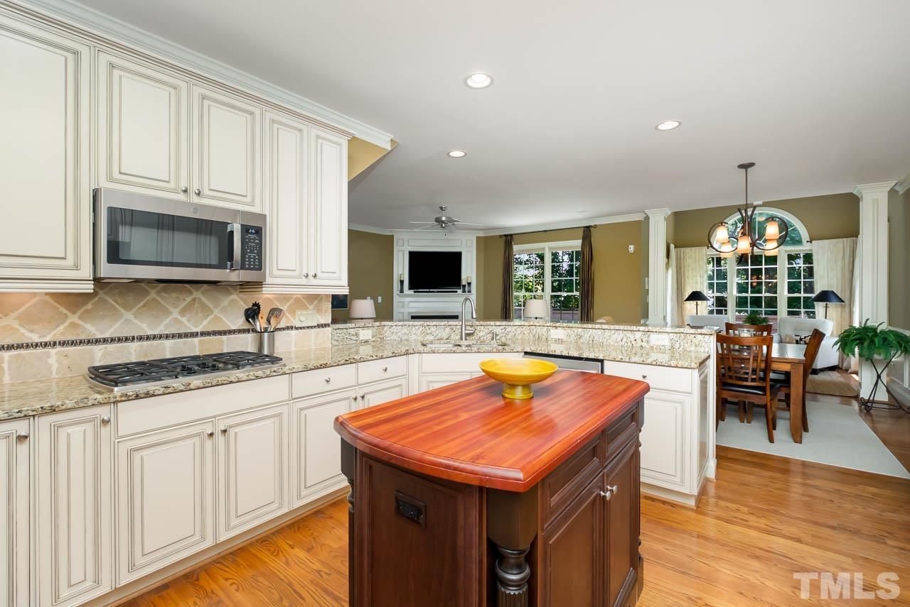 109 Nouveau Avenue Raleigh, NC 27615 - Photo 4 of 29 a kitchen with stainless steel appliances granite countertop a stove top oven a sink a dining table and chairs with wooden floor