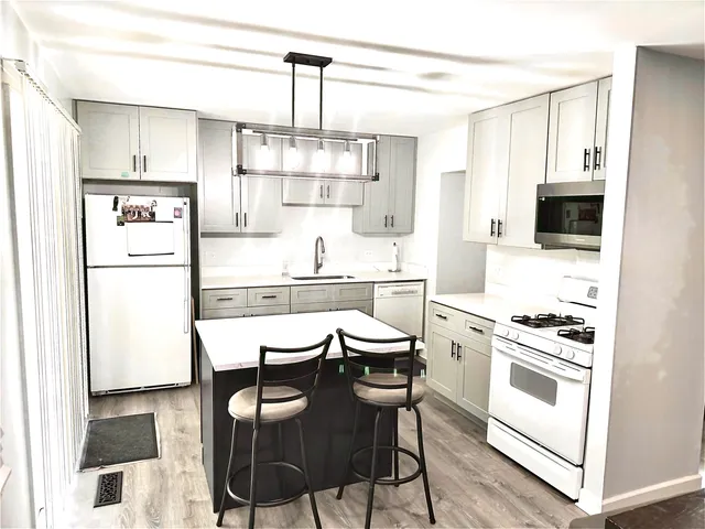 a kitchen with stainless steel appliances a white table chairs and a refrigerator