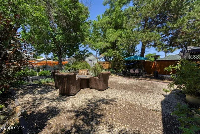 a view of a patio with table and chairs potted plants and large tree