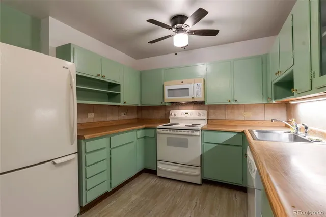 a kitchen with stainless steel appliances granite countertop a sink a stove a refrigerator a washer dryer and white cabinets